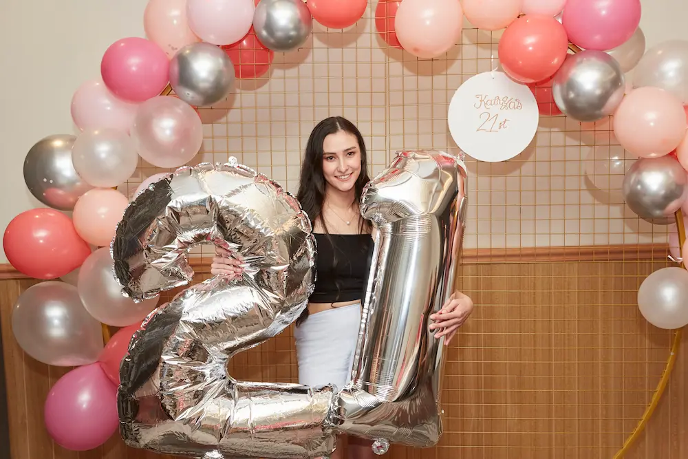 21st birthday girl photography holding balloons Birthday girl holding 21 balloon letters in front of a backdrop at her 21st birthday party