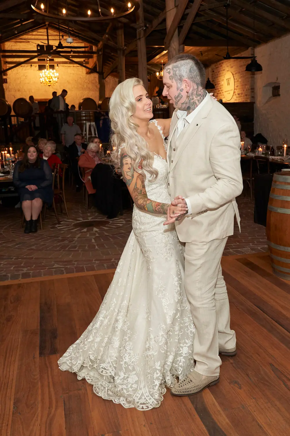 emma darko warrawong estate wedding first dance groom look Bride Emma and groom Darko sharing their first dance at Warrawong Estate, with Darko looking at Emma. The reception room is softly illuminated by chandeliers, creating a romantic atmosphere.