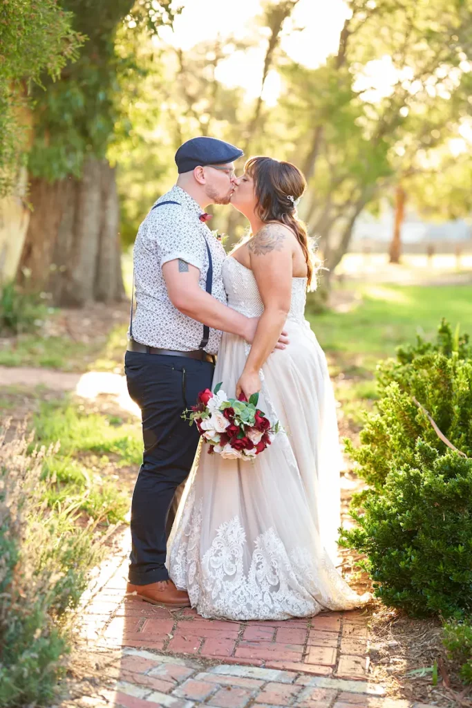 Bride and groom kissing with soft golden hour light shining through trees in the background