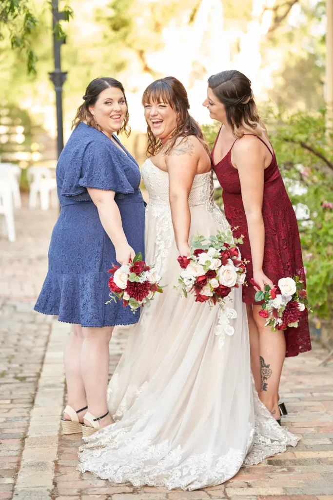 Bride and bridesmaids standing sideways, some looking back and laughing, holding bouquets with soft golden light