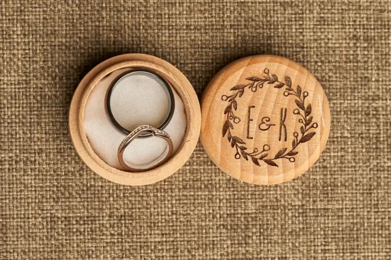 Close-up of wedding ring and wooden round beech ring box with initials on it during groom getting ready