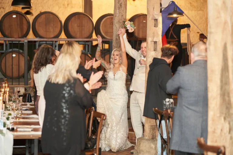 Bride Emma and groom Darko entering their wedding reception at Warrawong Estate, as guests stand and clap with joy and excitement to welcome them