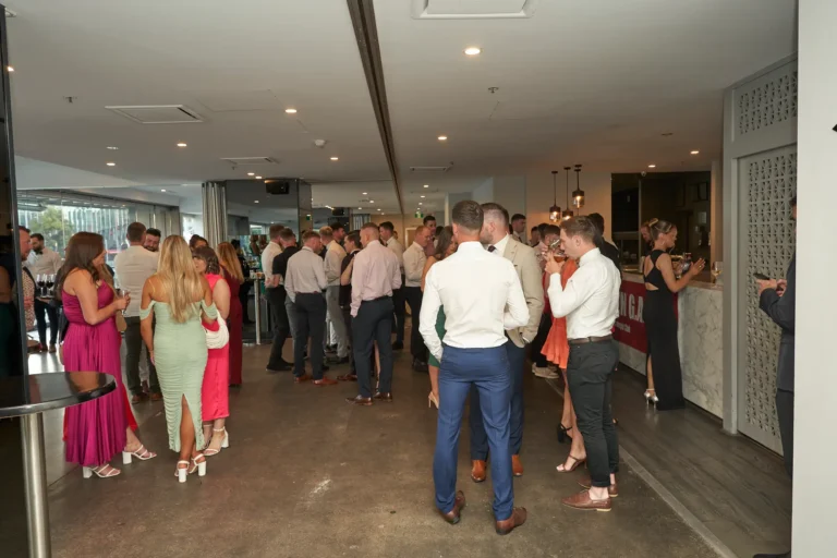 Wide shot of guests socializing and ordering drinks at the bar during the Garryowen Awards Night at River’s Edge Events, showing well-dressed individuals in a spacious indoor setting