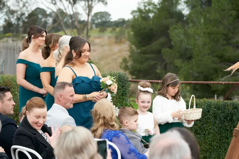 Candid shot of flower girls and bridesmaids during Emma and Darko’s Warrawong Estate wedding ceremony, with trees visible in the distance background